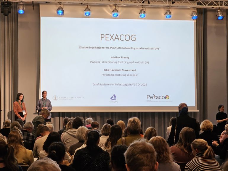 En gruppe mennesker foran en stor skjerm