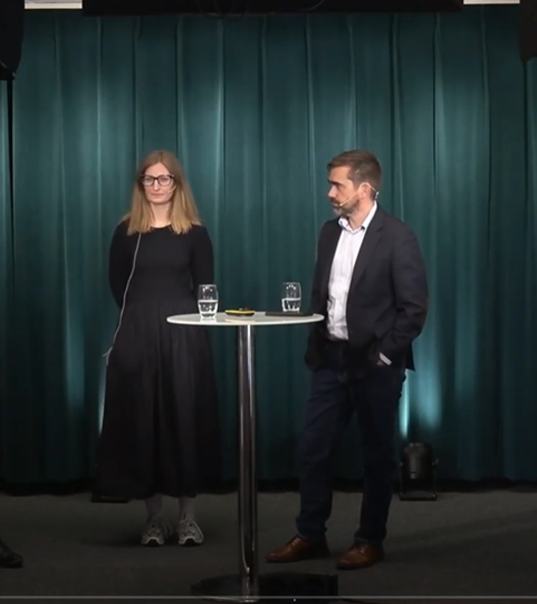 En mann og kvinne som står på et podium med et bord og en mikrofon