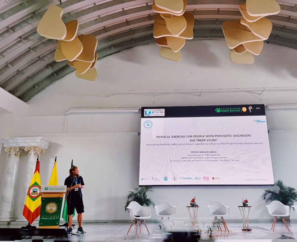 En person som står foran en skjerm med et stort hvitt skilt