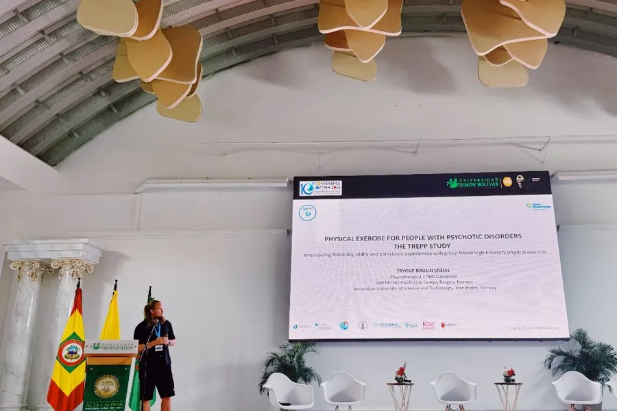 En person som står foran en skjerm med et stort hvitt skilt