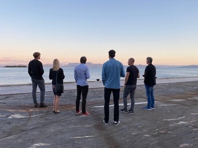 En gruppe mennesker som står på en strand og ser på vannet