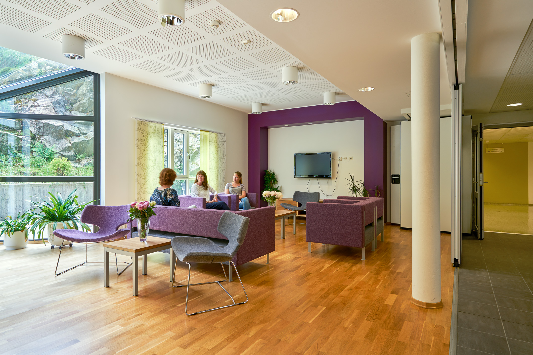 Et par kvinner som sitter ved et bord i et rom med en TV