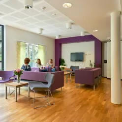 Et par kvinner som sitter ved et bord i et rom med en TV