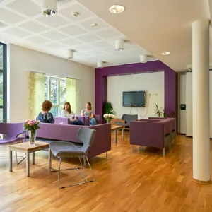 Et par kvinner som sitter ved et bord i et rom med en TV